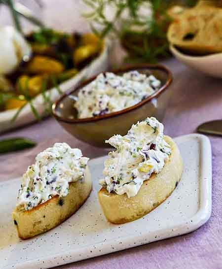Kreminio ir mėlynojo pelėsinio sūrio užtepėlė ant traškios duonelės su spanguolėmis, pistacijomis ir šviežiais rozmarinais