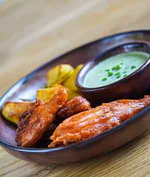 Fish and Chips alaus tešloje su keptomis bulvytėmis ir žaliųjų žirnelių padažu